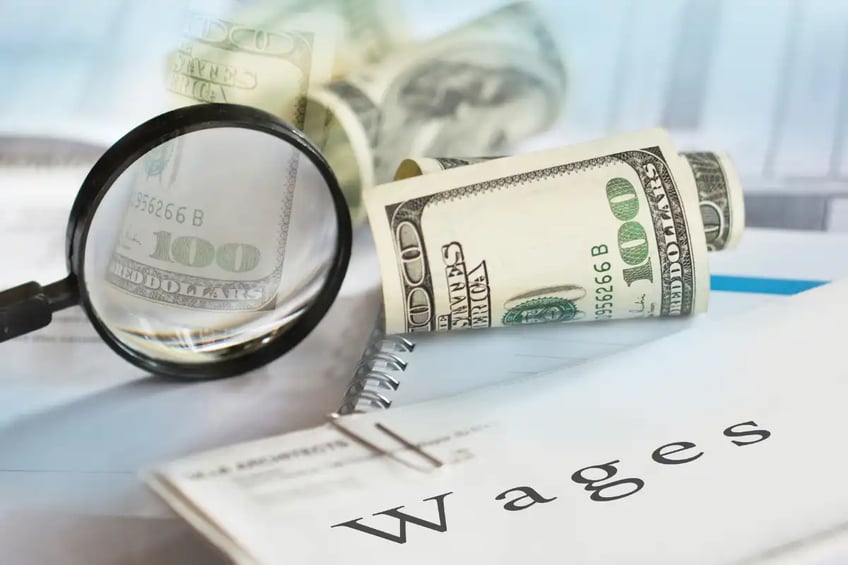 Magnifying glass, dollar notes, "Wages" written on paper