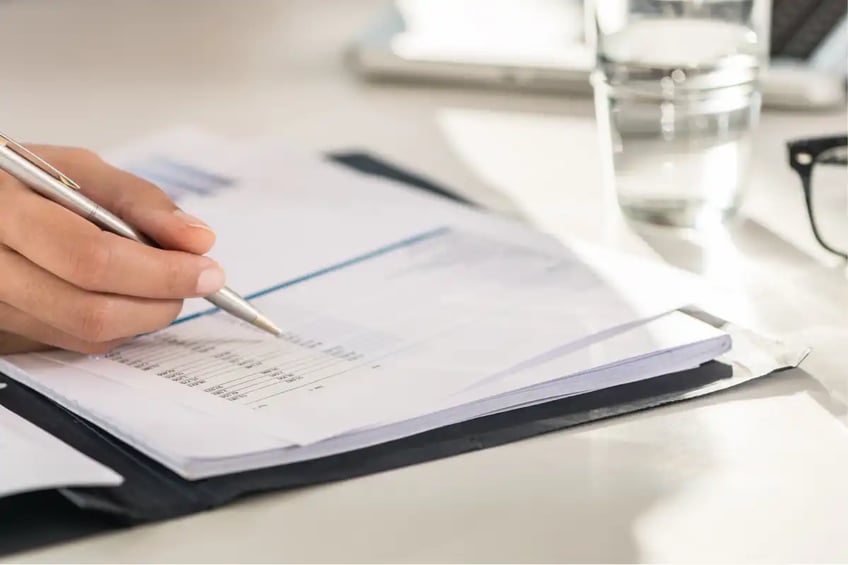 Hand with pen checking items on a sheet