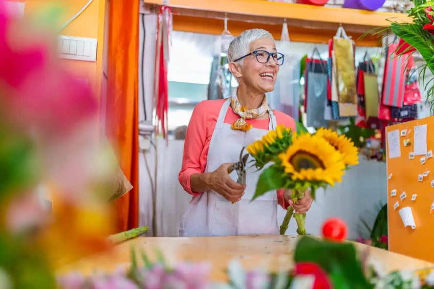 A smiling flower seller holding yellow flowers in her shop