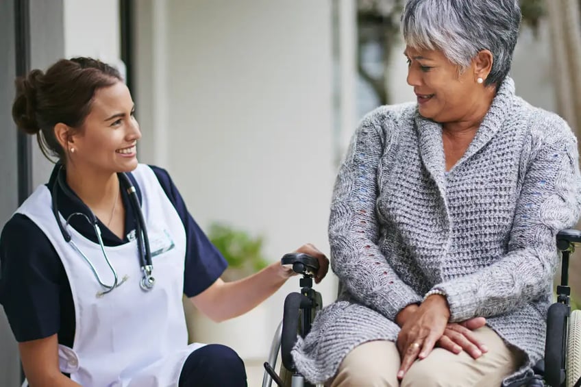 Medical nurse talking to an elderly woman in a wheelchair